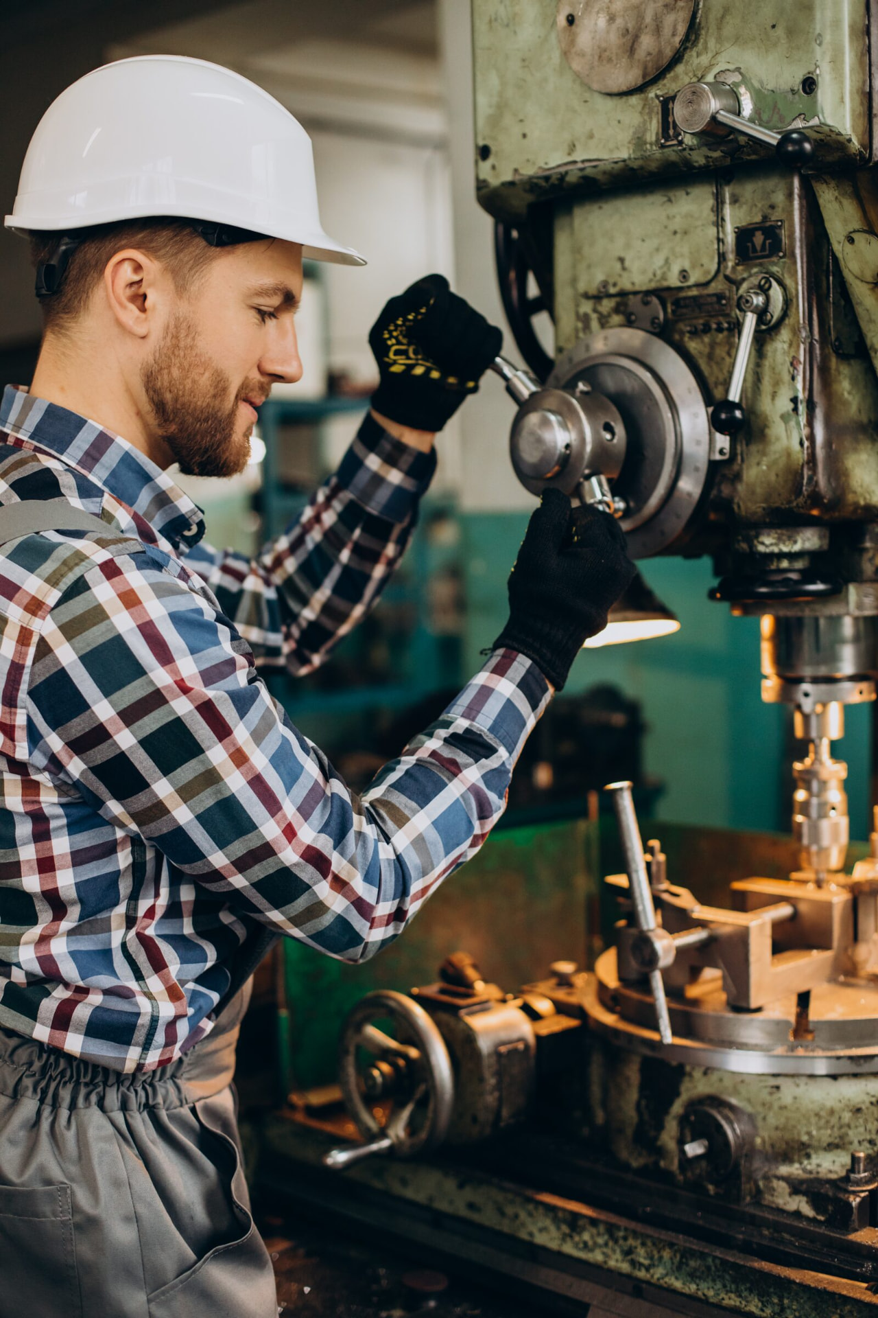 Engineer operating a pillar drill in a workshop