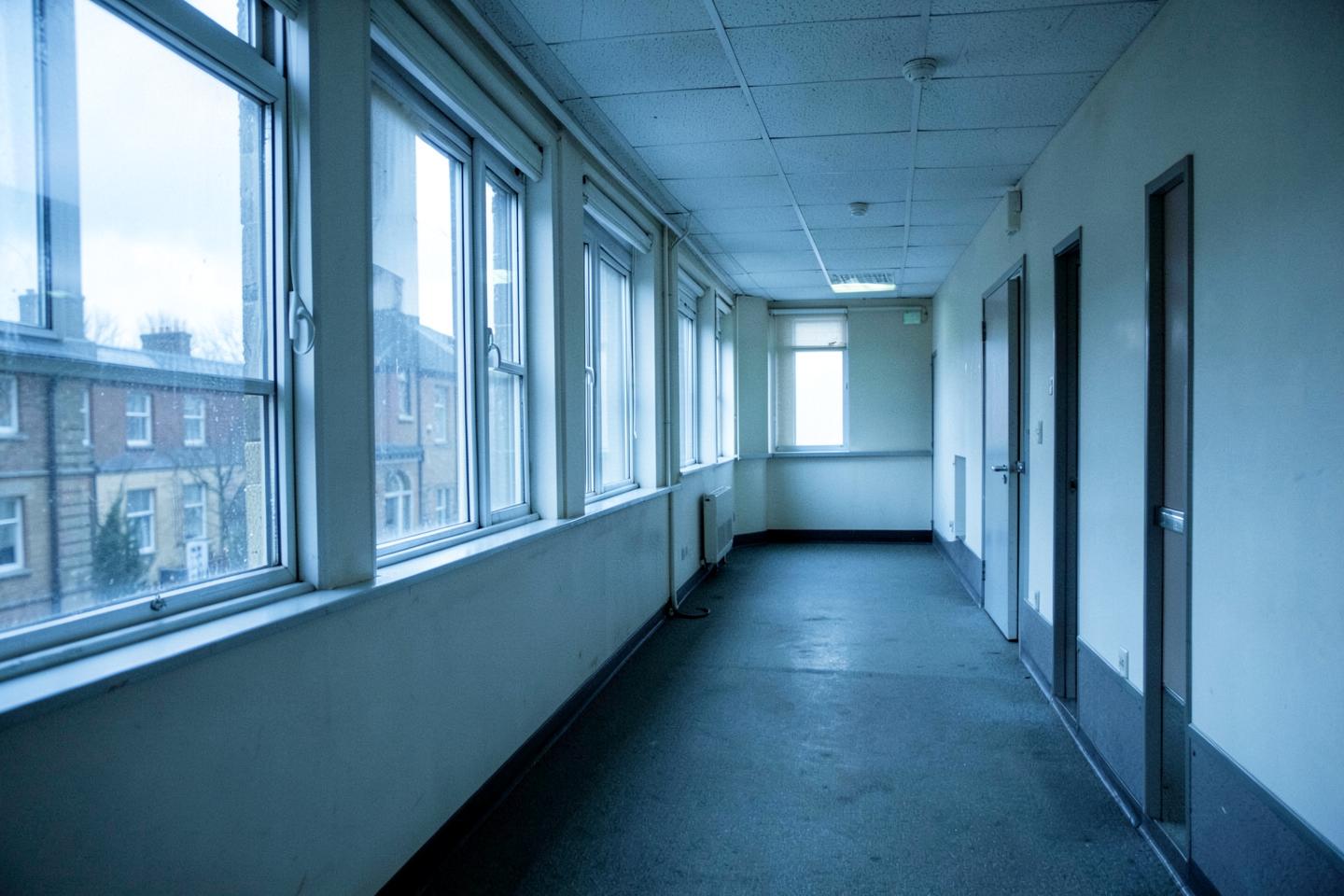 Empty office corridor lit by daylight from a row of windows
